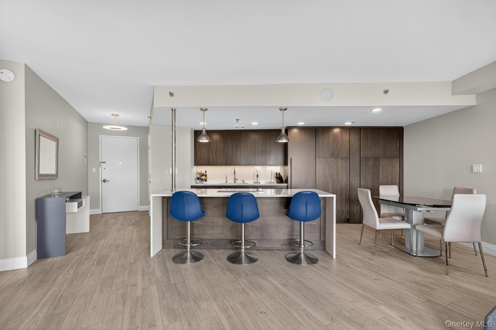 Open kitchen featuring a waterfall Quartz center island, breakfast bar, custom cabinets and modern high end appliances