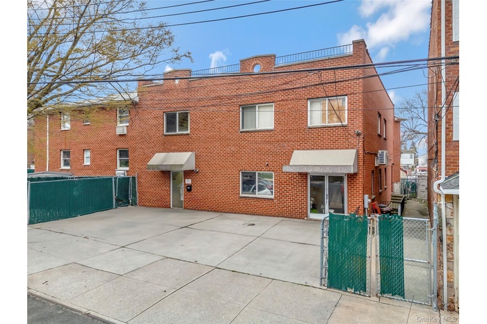 Back of house with fence, brick siding, an AC wall unit, and a gate