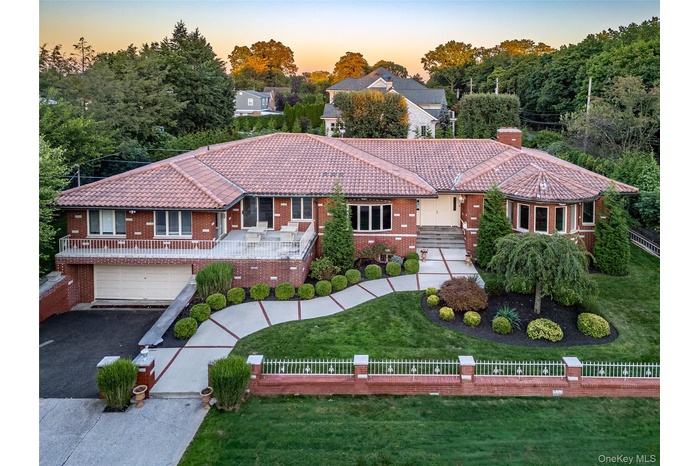 View of front of property featuring a fenced front yard, a tiled roof, and driveway