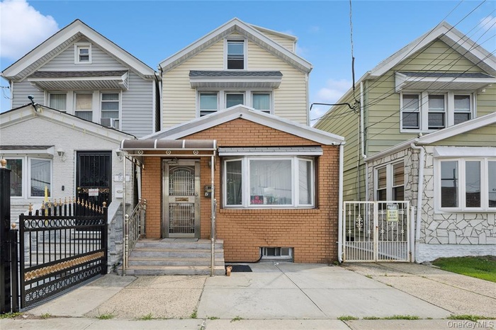 View of front of home with a gate and brick siding