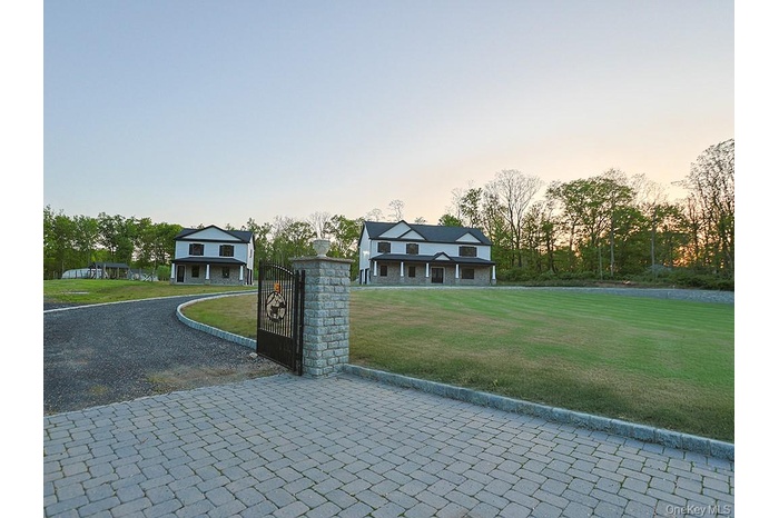 View of front of property with a front yard, a gate, and driveway
