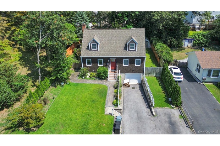 View of front of house featuring an attached garage, asphalt driveway, a front lawn, a shingled roof, and a chimney