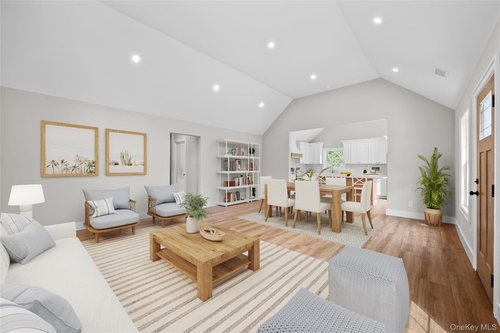 Living area featuring light wood-type flooring, recessed lighting, and high vaulted ceiling