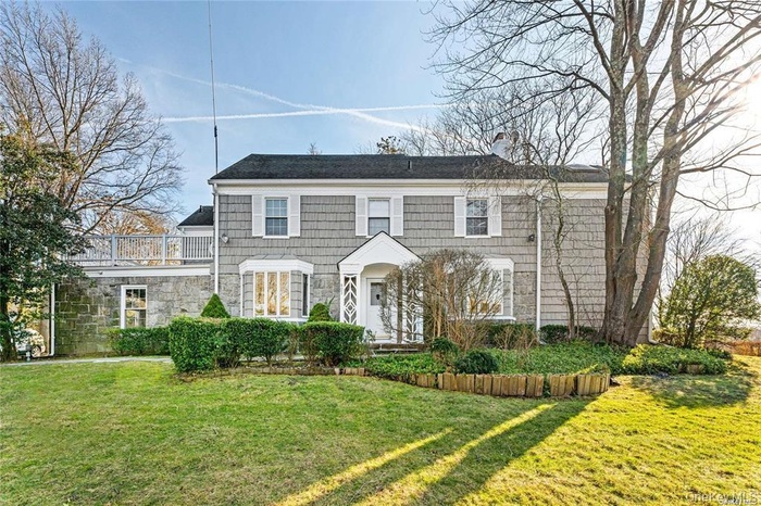 View of front facade featuring a front lawn, a chimney, and stone siding