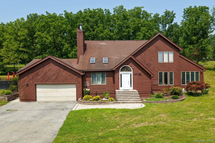 Rustic home with driveway, an attached garage, a front yard, a chimney, and roof with shingles