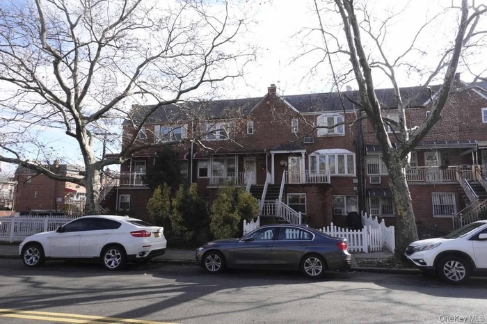 View of front of property with stairs, a chimney, and brick siding