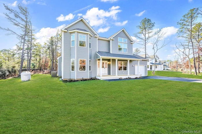 View of front facade with driveway, a porch, a front yard, and a garage