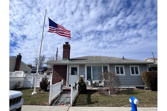 View of front of home featuring a chimney, a front yard, fence, and a gate