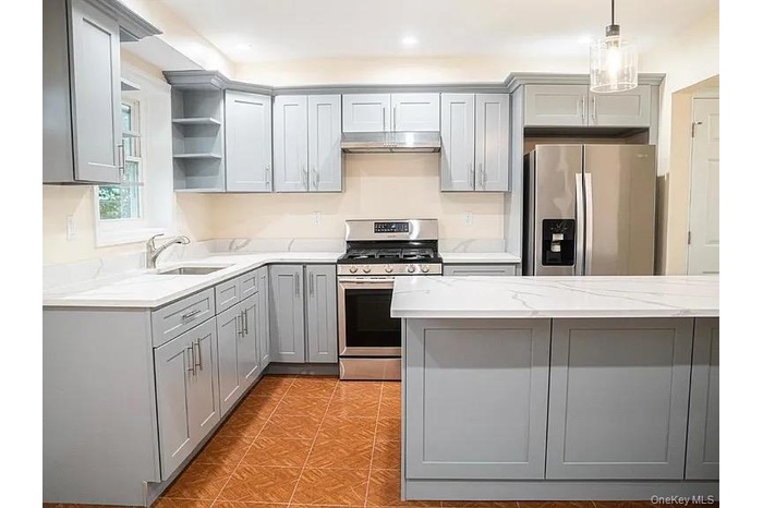 Kitchen featuring a sink, under cabinet range hood, open shelves, gray cabinetry, and appliances with stainless steel finishes