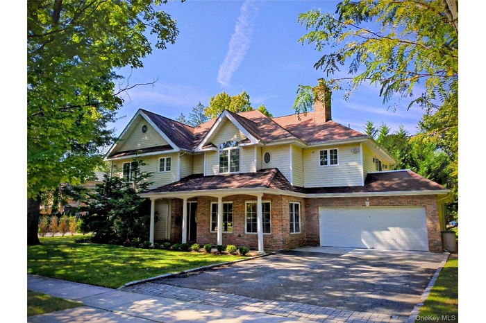 View of front of home featuring a porch, driveway, brick siding, and a garage