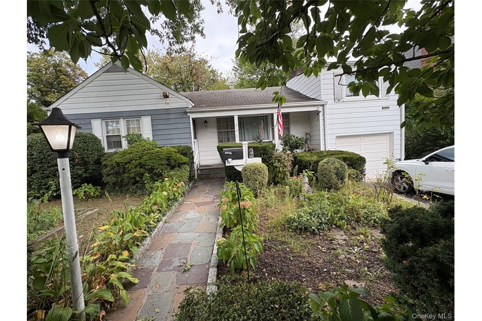 Tri-level home featuring a porch, a garage, and a shingled roof