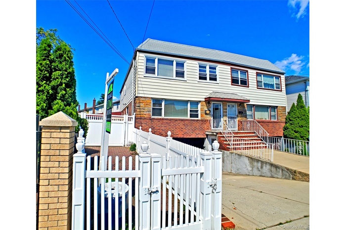 View of front facade featuring a gate, a fenced front yard, brick siding, and a shingled roof
