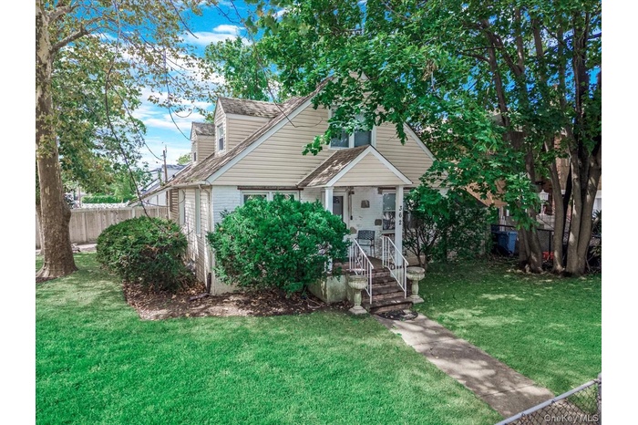 View of front facade with a shingled roof and covered porch
