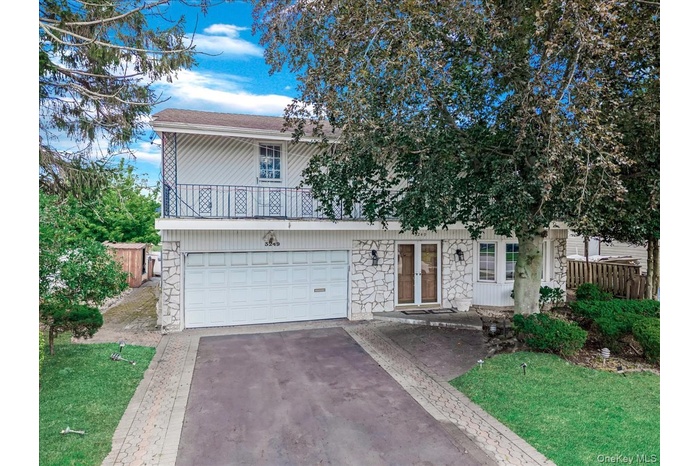 View of front of house featuring stone siding, driveway, and an attached garage