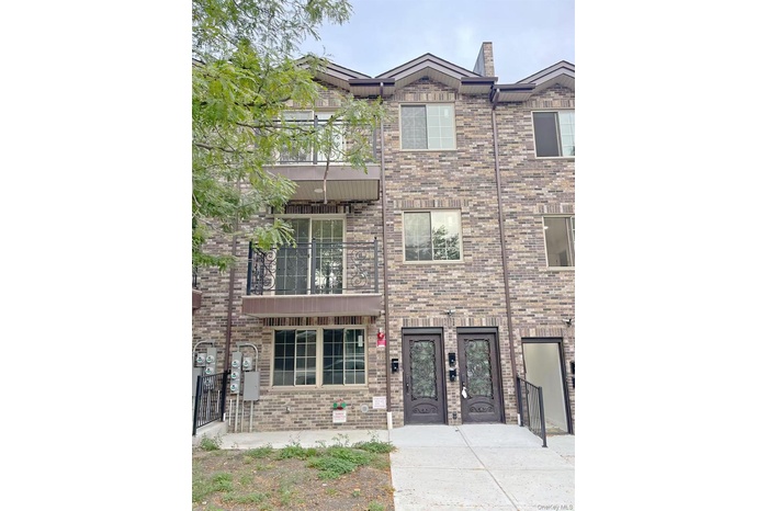 View of front of property with brick siding and a balcony