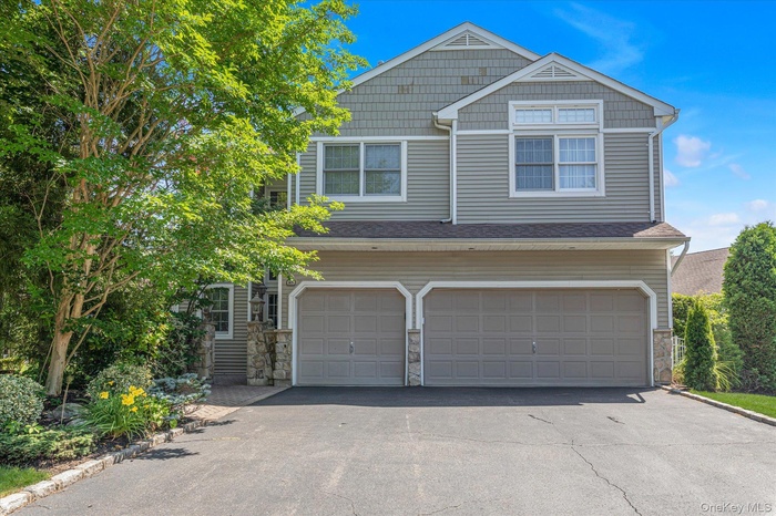 View of front facade with asphalt driveway, an attached garage, and stone siding