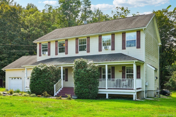 View of front of home with a porch, a 2 car garage, and front yard.