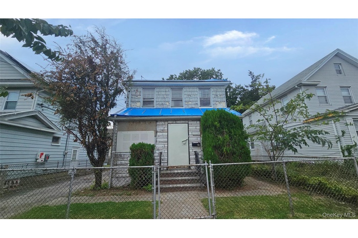 View of front of house with stone siding, a gate, a fenced front yard, a metal roof, and a standing seam roof