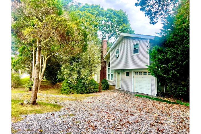 View of front of home with a chimney, driveway, and an attached garage