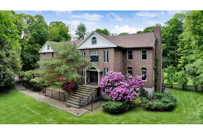 View of front of home with brick siding, a chimney, and stairway