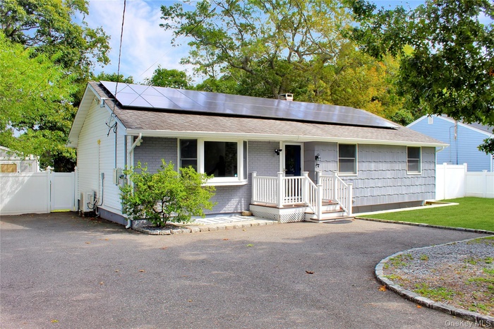 View of front facade with roof with shingles, solar panels, and covered porch
