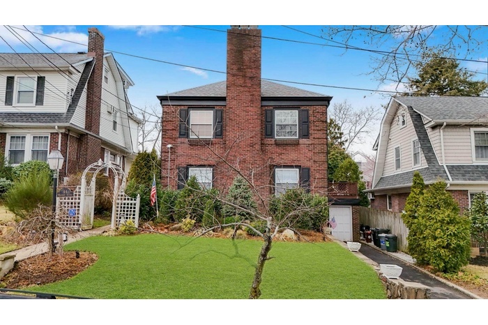 View of front of property with brick siding, roof with shingles, and a front lawn
