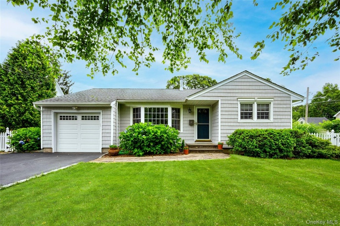 Ranch-style house featuring an attached garage, asphalt driveway, and roof with shingles