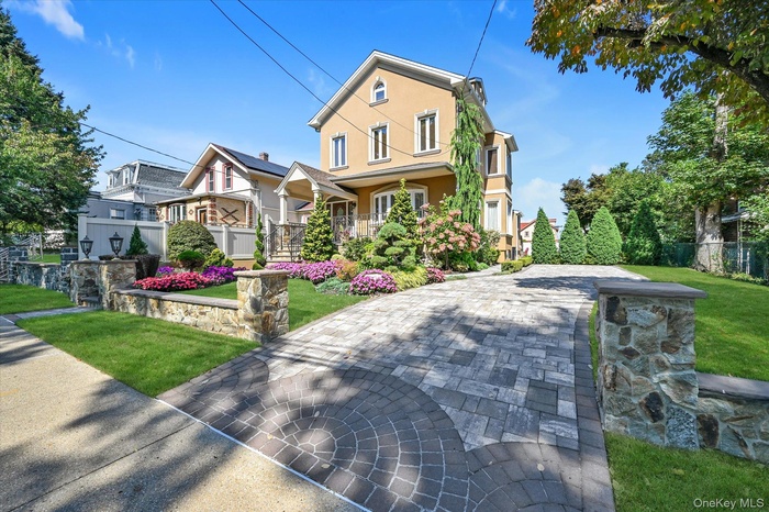 View of front of home featuring stucco siding, a porch, and decorative driveway