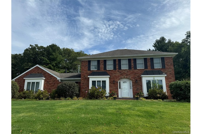 Colonial house featuring brick siding and a front lawn