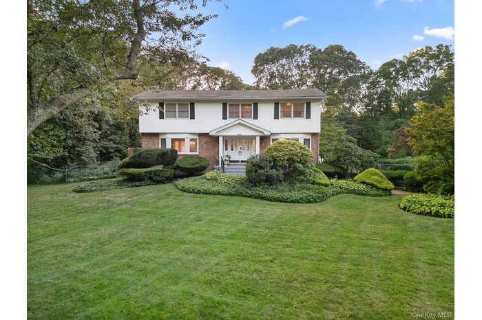 View of front of house featuring brick siding, a front lawn, and view of scattered trees