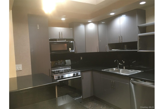 Kitchen featuring dark countertops, stainless steel appliances, gray cabinets, open shelves, and recessed lighting