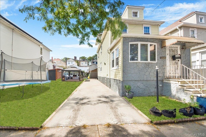 View of front of home with a front yard, concrete driveway, and a trampoline