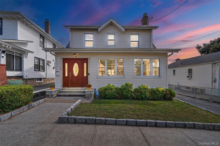 View of front of house with a chimney and a front lawn