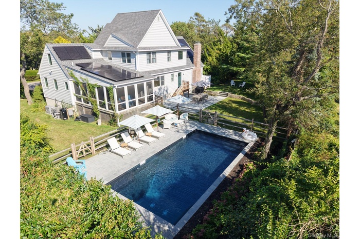 Rear view of house featuring a sunroom, a patio, a fenced backyard, and a shingled roof