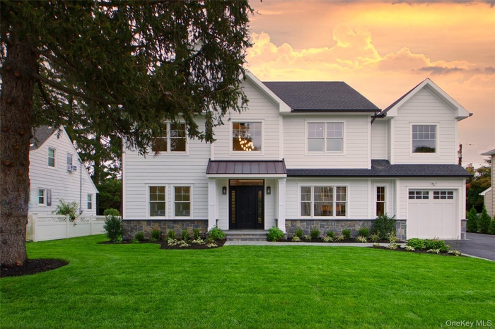 View of front facade with stone siding, a garage, roof with shingles, and asphalt driveway