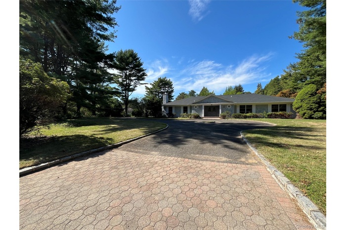 Ranch-style house featuring decorative driveway and a front yard