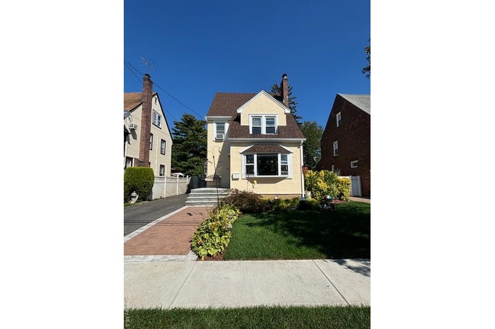 View of front facade with a chimney, stucco siding, and a shingled roof