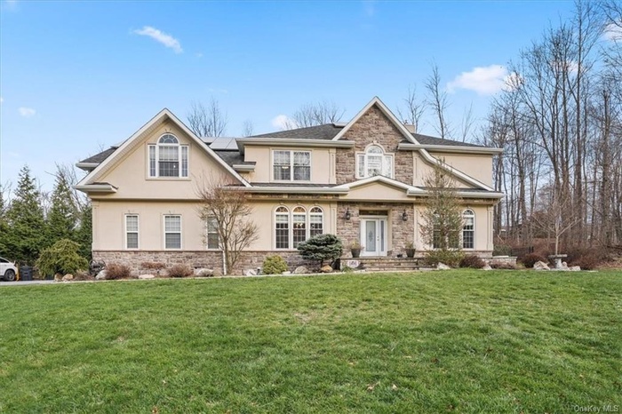 Craftsman house featuring a front lawn, stucco siding, stone siding, and solar panels