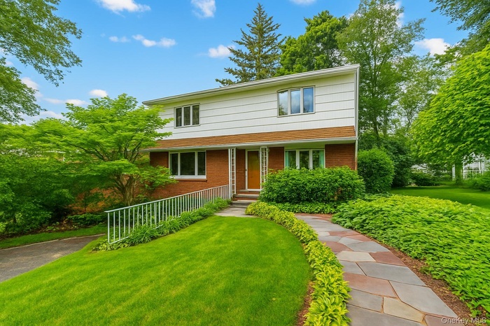 View of front of property featuring a front yard and brick siding (color of grass edited)