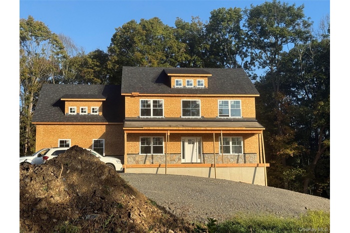 View of front of property featuring a porch, stone siding, and a shingled roof