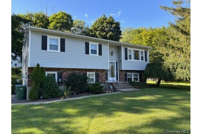 Bi-level home with a front lawn and brick siding