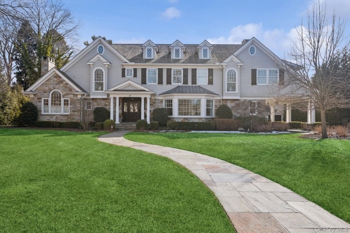 View of front facade with stone siding, a front yard, and a chimney