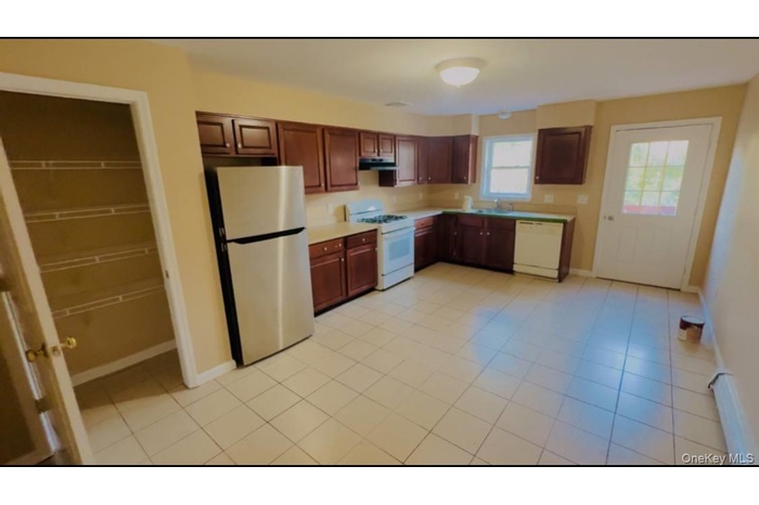 Kitchen featuring white appliances, light countertops, under cabinet range hood, and light tile patterned flooring