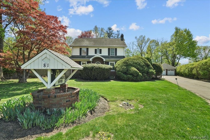 View of front of property with a chimney, a front yard, and a garage