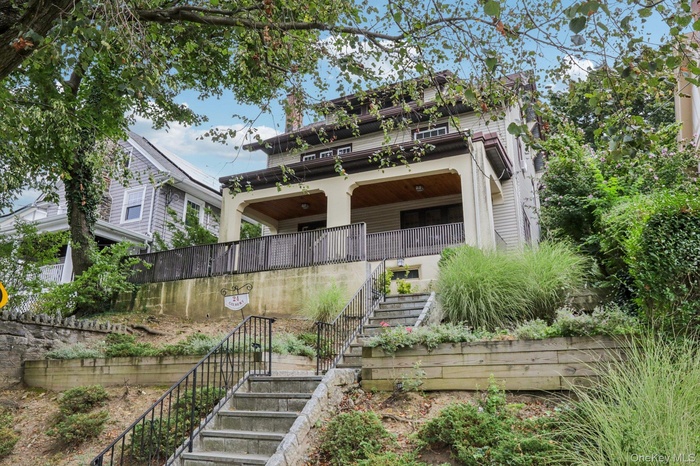 View of front of home with stairway and a balcony