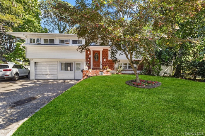 View of front of property featuring a front yard, asphalt driveway, an attached garage, and brick siding