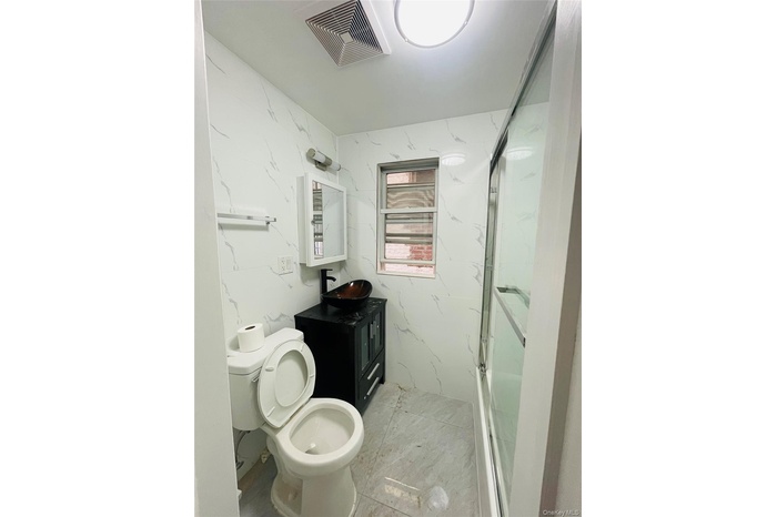 Bathroom featuring vanity and a marble finish shower