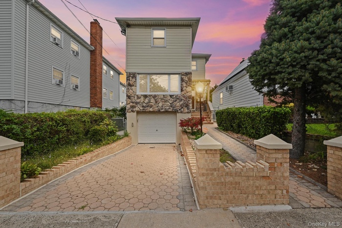 View of front of house featuring decorative driveway, stone siding, and an attached garage