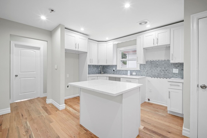 Kitchen featuring white cabinetry, decorative backsplash, light wood-style floors, a center island, and recessed lighting