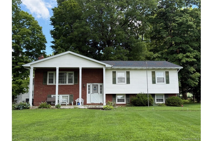 Split foyer home with a front yard, brick siding, and covered porch